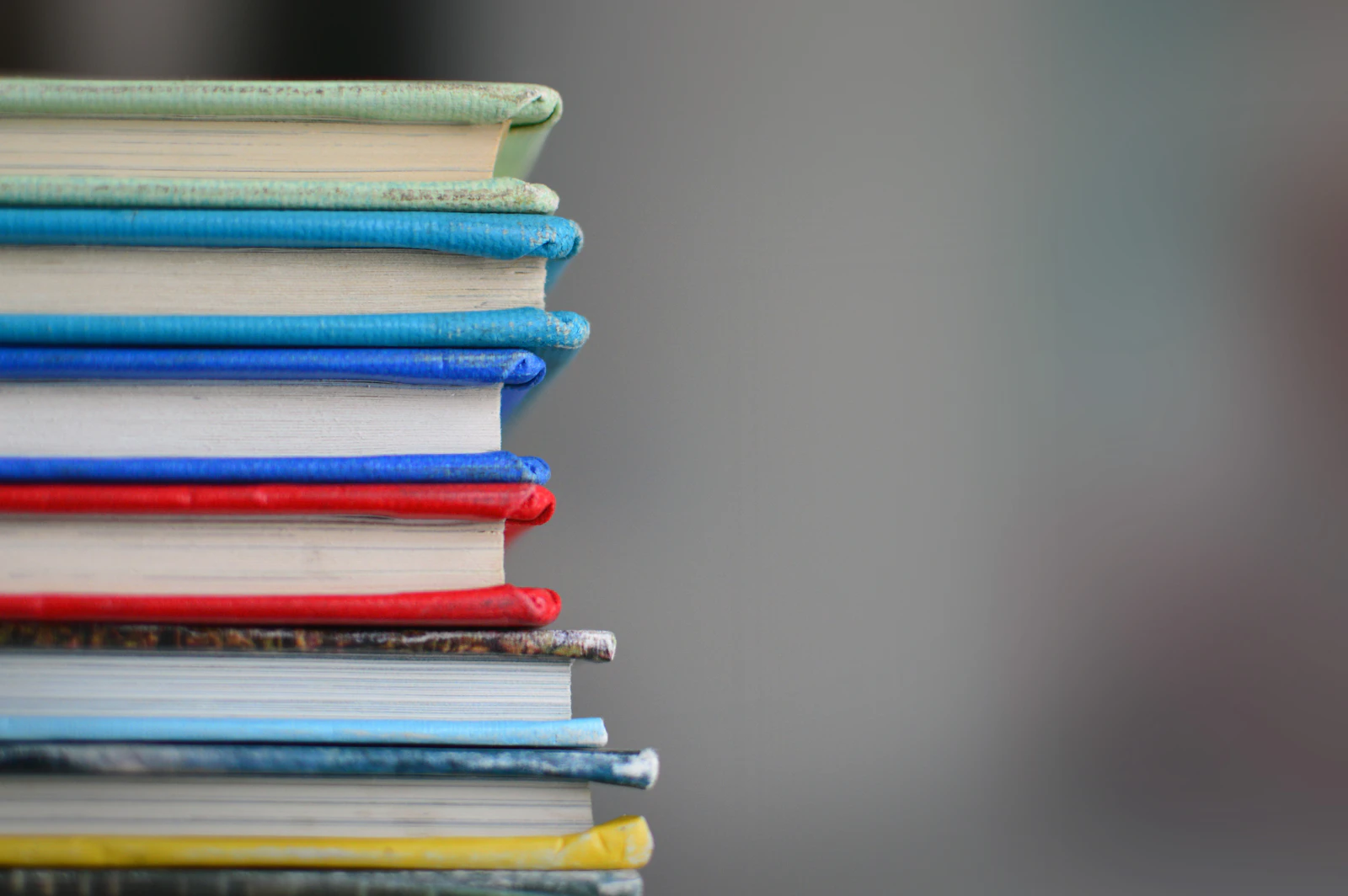 Pile de livres reliés aux tranches colorées bleues, rouges, vertes et jaunes