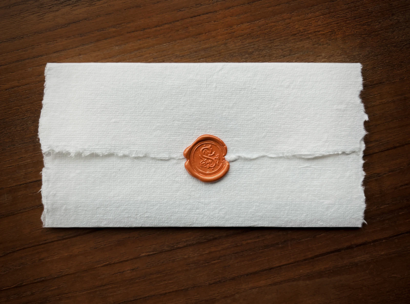 Lettre en papier fait main fermée par un cachet de cire cuivré