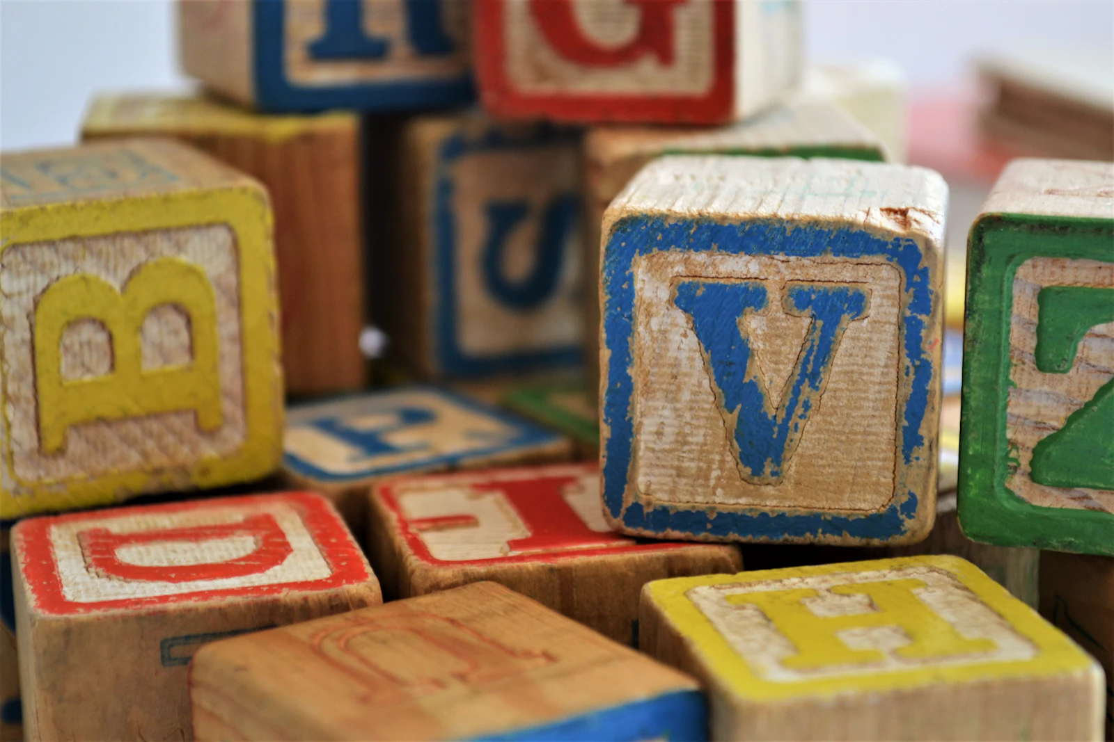 Vieux cubes alphabet en bois aux couleurs usées, posés en vrac sur une table