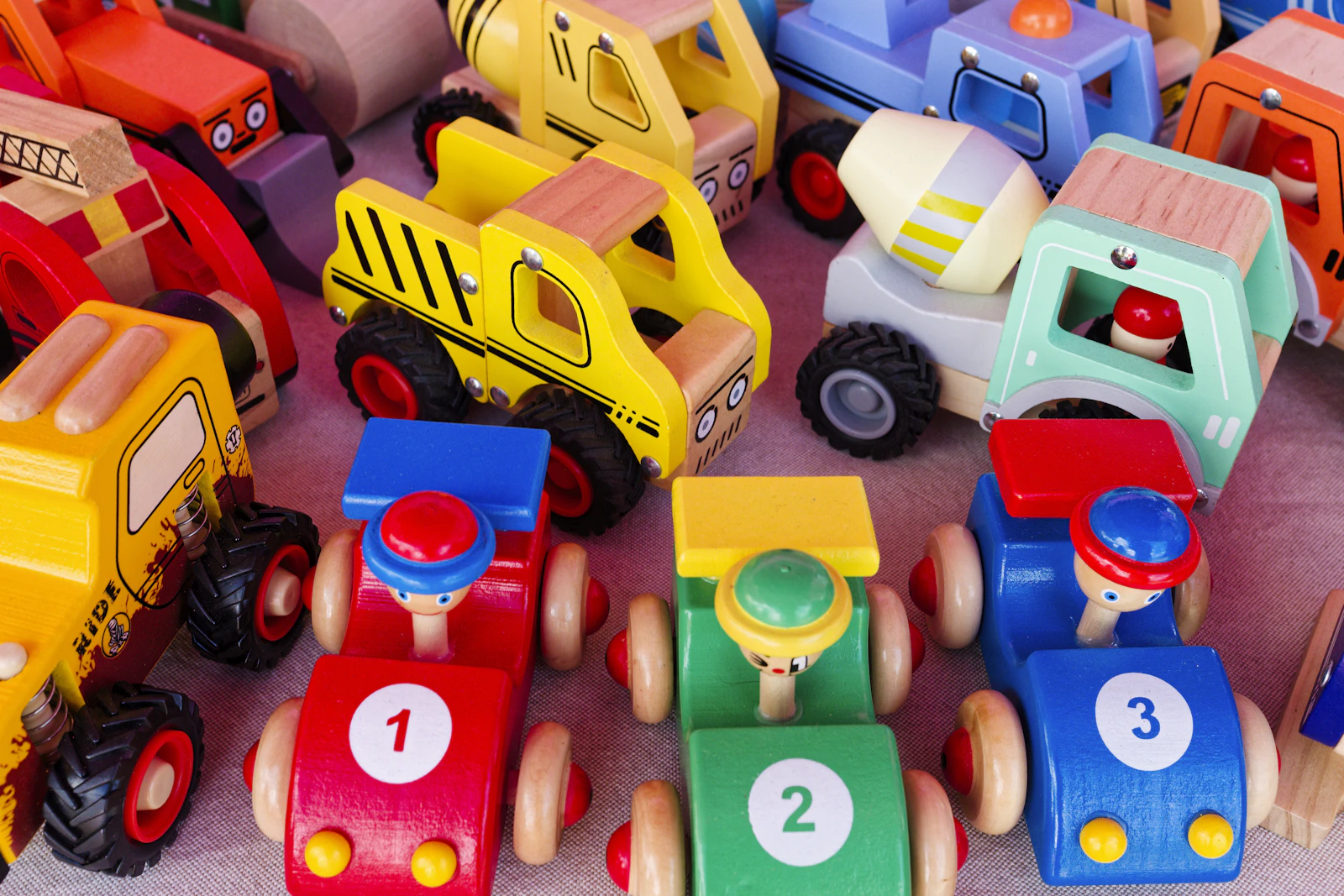 Petites voitures et camions en bois colorés, alignés côte à côte sur une table