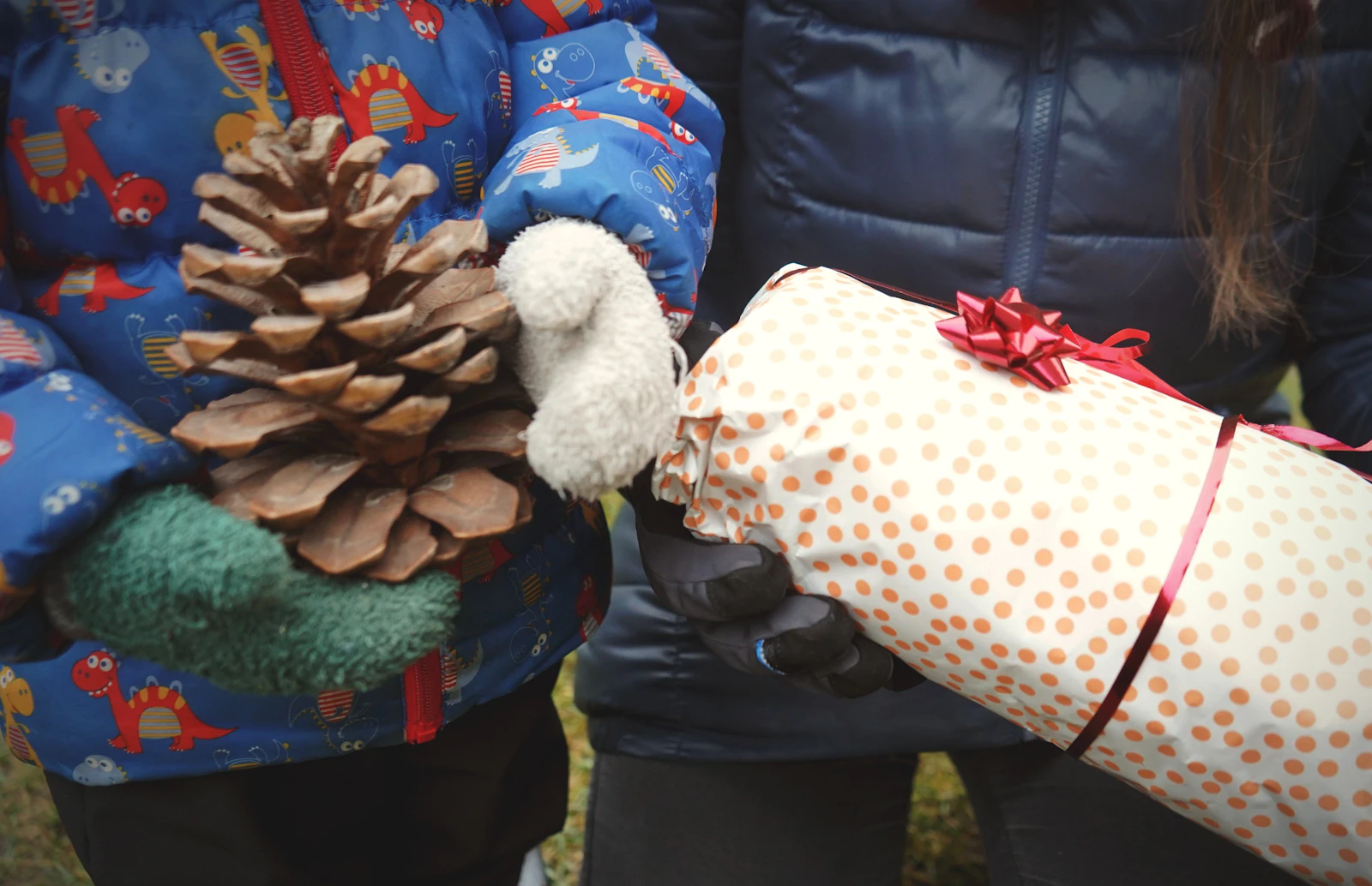 Deux paires de mains tenant un cadeau de Noël emballé à la maison