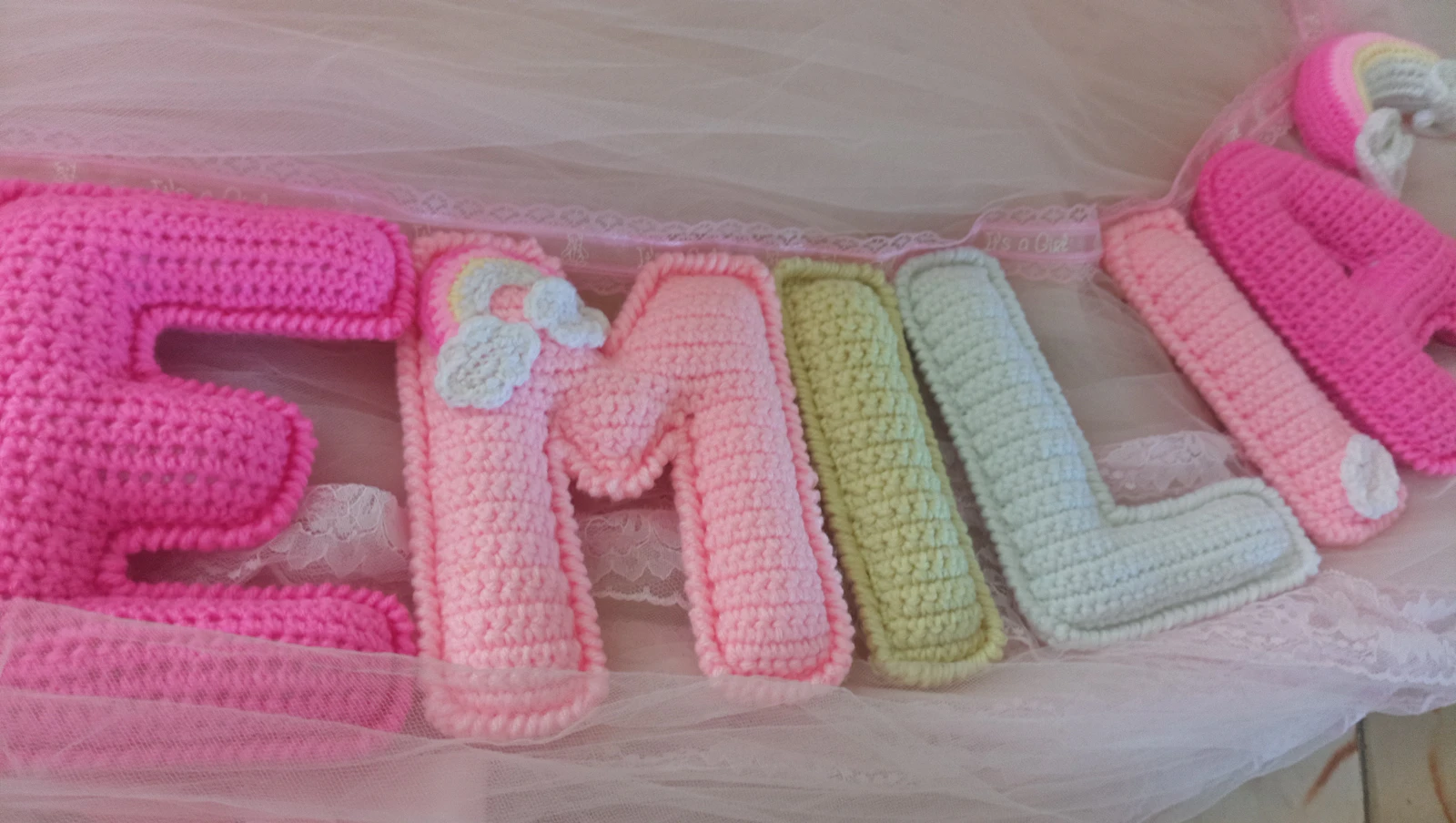 Lettres au crochet aux couleurs pastel formant le prénom d'une petite fille