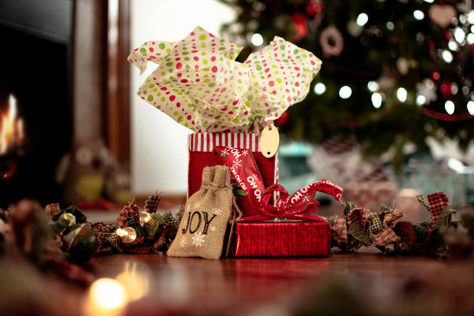 Petits cadeaux emballés et guirlande en tissu au pied d'un sapin illuminé