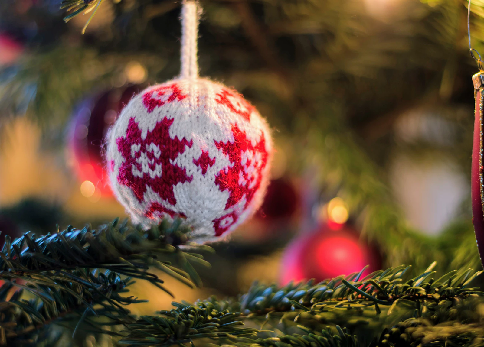 Boule de Noël tricotée blanche et rouge suspendue à une branche de sapin