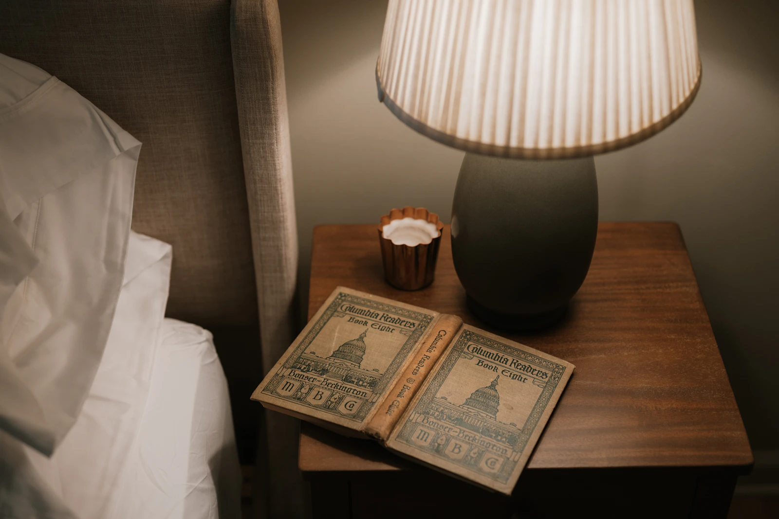 Livre ouvert sur une table de chevet éclairée par une lampe à abat-jour