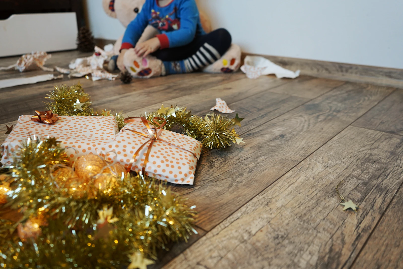 Paquets à pois sur un parquet, enfant flou en arrière-plan entouré de papier déchiré