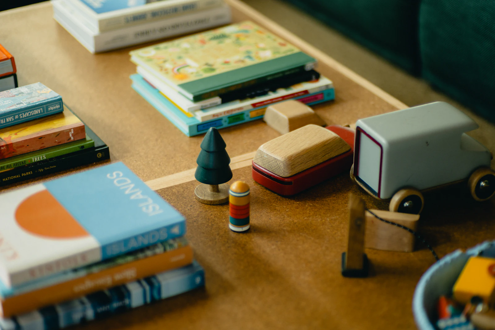Jouets en bois, petit sapin tourné et piles de livres illustrés sur une table
