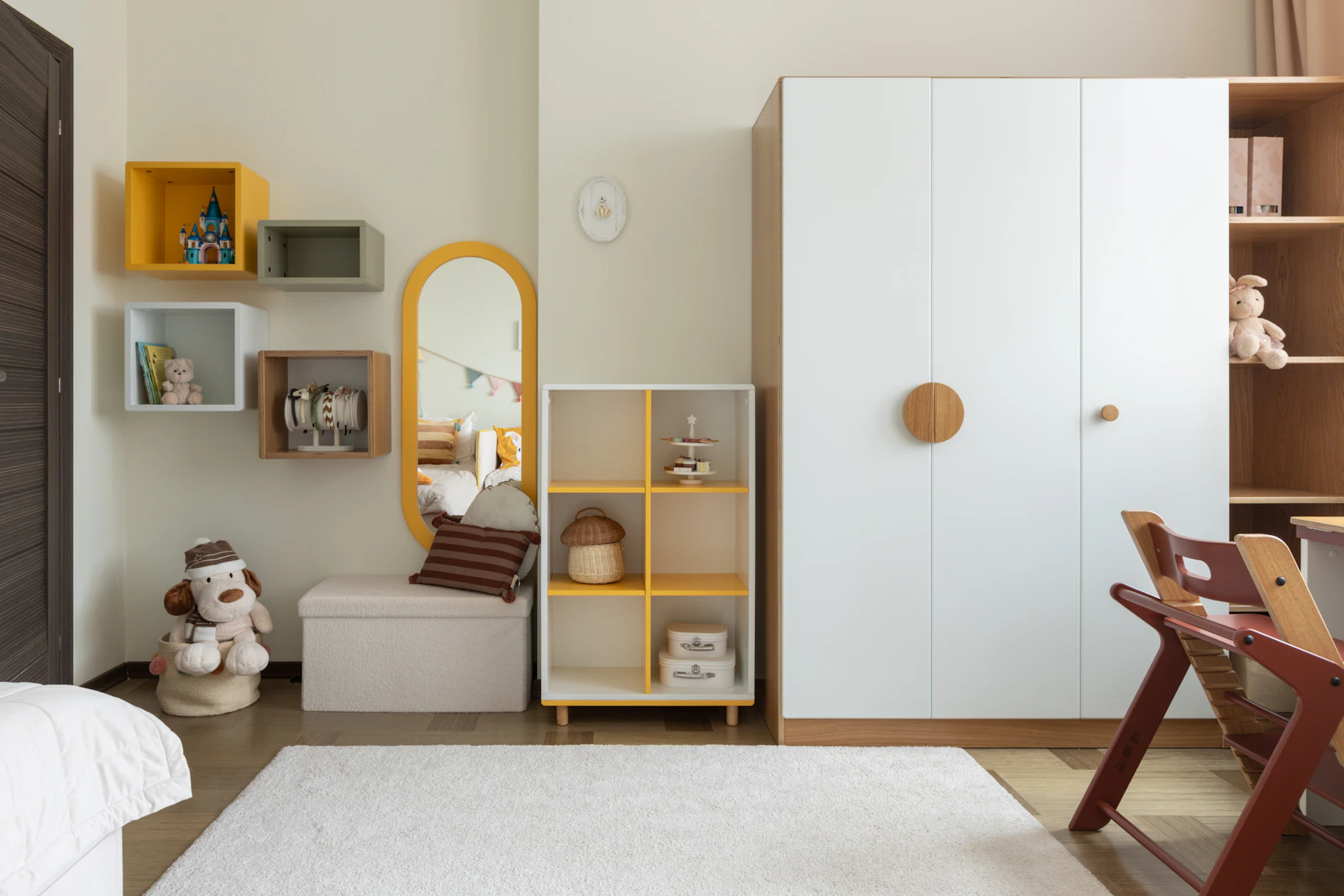 Chambre d'enfant rangée avec étagère basse, cubes muraux, peluches et tapis blanc