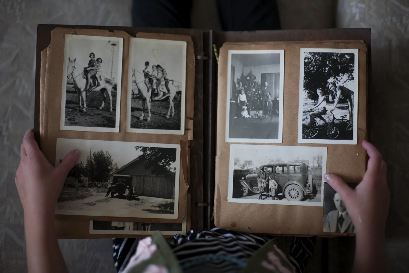 Deux mains ouvrant un vieil album de photos de famille en noir et blanc